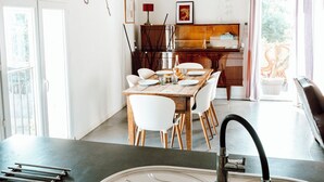 Une cuisine moderne dotée d’un grand îlot central, d’un coin repas et offrant une vue sur l’extérieur.