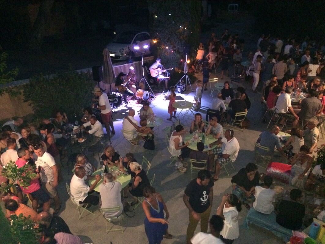 Evento al aire libre con escenario y público sentado en sillas.