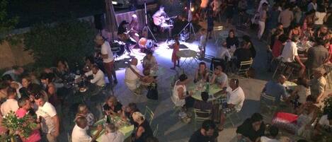 An outdoor event with a stage and audience seated on chairs.