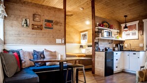 A cozy living area with a sofa, a dining table, and a kitchen area with a microwave and cabinets. - SWEET HILL COUNTRY CABIN in the PERFECT location;  Sleeps 4-5 (Dripping Springs)