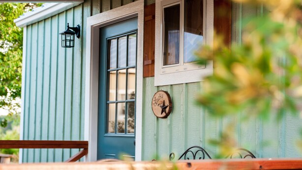 A rustic wooden porch with a blue door and a small window. - SWEET HILL COUNTRY CABIN in the PERFECT location;  Sleeps 4-5 (Dripping Springs)