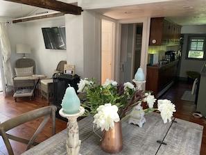 A dining area with a table set for two, featuring a vase with flowers and candle holders.