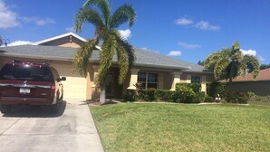 A residential house with a driveway, a parked SUV, and a well-maintained lawn.