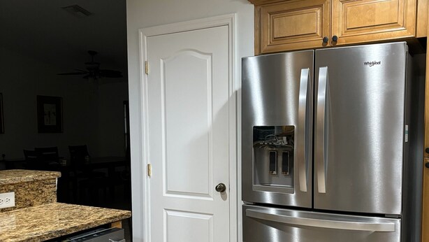 A kitchen with a stainless steel refrigerator, a dishwasher, and wooden cabinets.