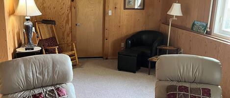 A living room with two leather armchairs, a small round table, and a wooden door.