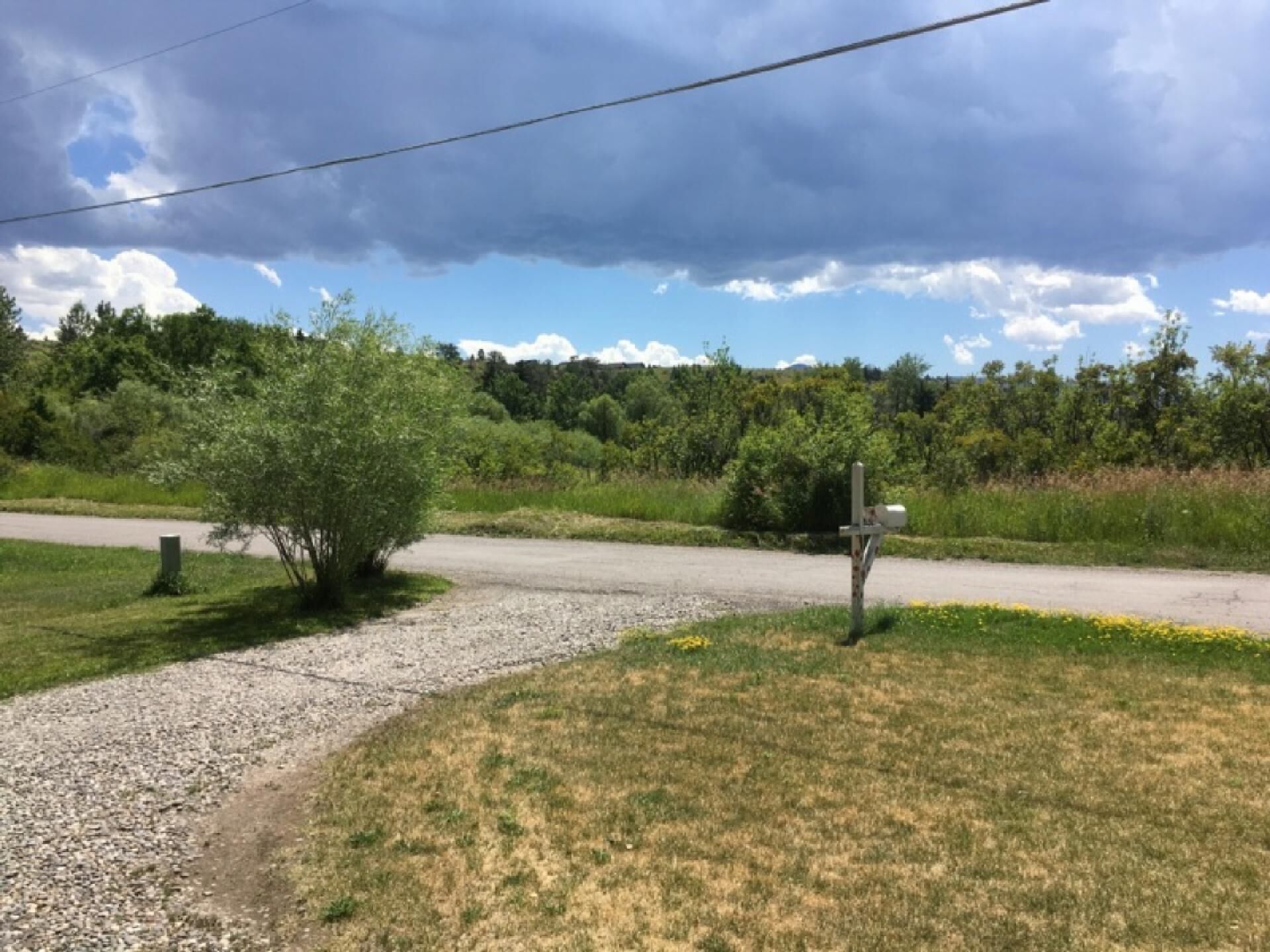 A rural road with a gravel path and a mailbox on the right.