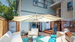 Un patio con un sofá blanco, una silla blanca y una mesa con un tapete a rayas.