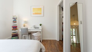 Un dormitorio con una cama, un escritorio, una silla, una estantería y un cuadro en la pared.