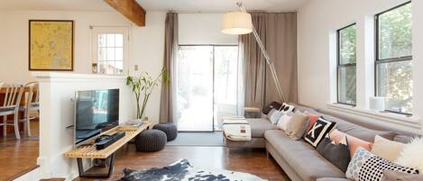 A modern living room with a wooden ceiling, a television, a sofa, and a large window.