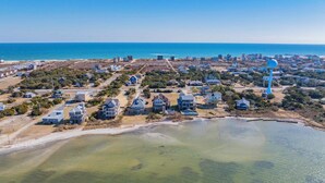 Vista aérea de una zona residencial costera con casas, una playa y una gran escultura azul.