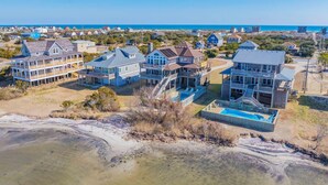 Una zona residencial costera con varias casas de dos pisos, balcones y una piscina.