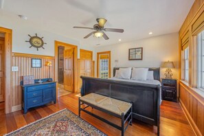 Une chambre à coucher comprenant un lit, un banc, une commode, un ventilateur de plafond et un tapis.