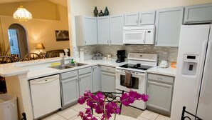 A modern kitchen with white cabinetry, a built-in oven, a microwave, and a coffee maker. - Private Pool house with private pool, near all famous attractions!!! (Kissimmee)