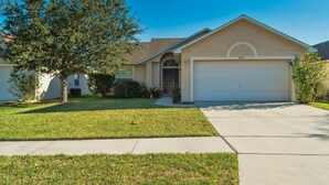 A single-story house with a garage, a well-maintained lawn, and a tree in the front yard. - Private Pool house with private pool, near all famous attractions!!! (Kissimmee)