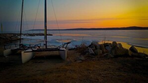 Purjevene on ankkuroitu kivikkoiseen rantaan, ja taustalla näkyy auringonlasku.