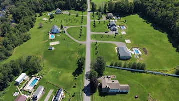 An aerial view of a residential area with multiple houses, a swimming pool, and a well-maintained lawn.
