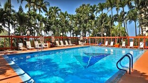 A swimming pool with lounge chairs and palm trees in the background.