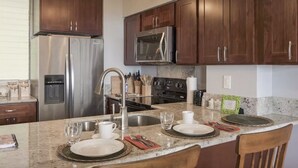 A modern kitchen with dark wood cabinets, stainless steel appliances, and a granite countertop.