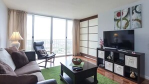 A modern living room with a sofa, a chair, a coffee table, a TV, and a bookshelf.
