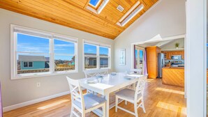 Un'ampia sala da pranzo con soffitto in legno, grandi finestre e vista sul quartiere.