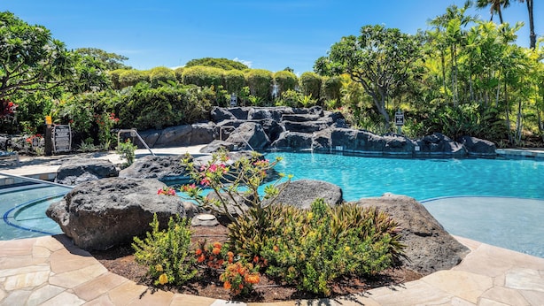 A swimming pool surrounded by tropical plants and rocks. - Hilton Waikoloa Pool Pass for stays in 2026/Waikoloa Golf Discounts (Waikoloa Beach Resort)