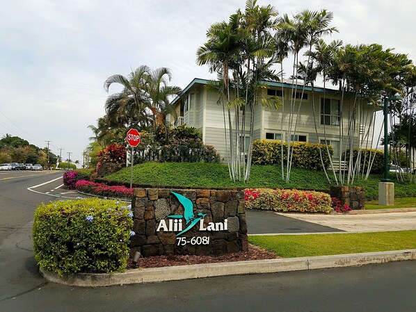 A building with a stone sign reading "Alii Lani 75-6081" and a stop sign.