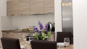 A modern kitchen with wooden cabinets, a stainless steel refrigerator, and a dining area with a table set for two. - Entire home. Private entrance. 5 minutes walk to shops and sea front.  (Sliema)