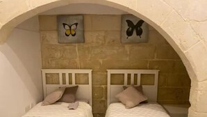 Two single beds with headboards, a stone wall, and butterfly wall art. - Entire home. Private entrance. 5 minutes walk to shops and sea front.  (Sliema)