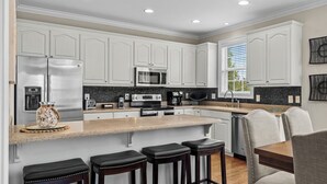 A modern kitchen with white cabinets, stainless steel appliances, and a granite countertop.