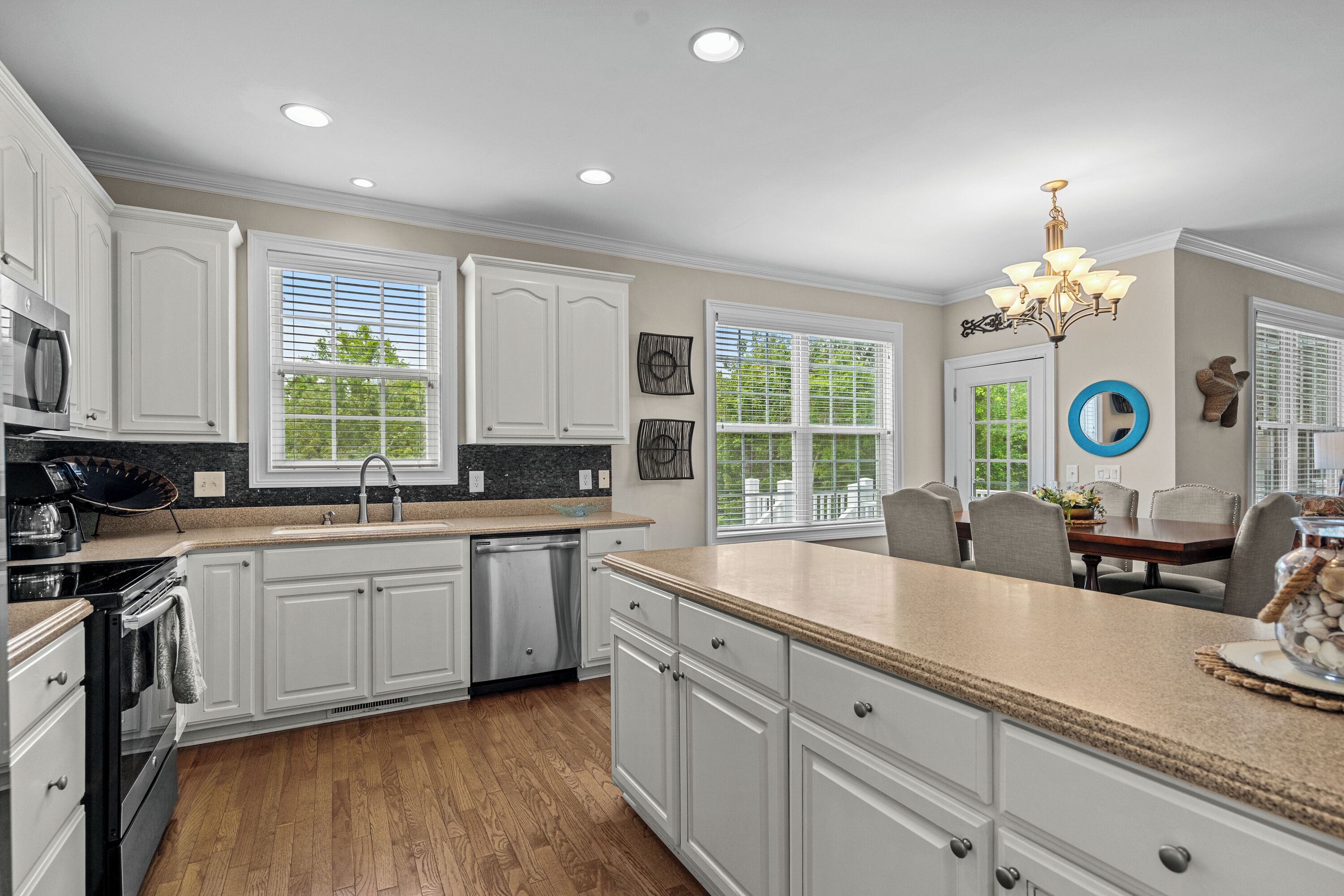 A modern kitchen with white cabinetry, a granite countertop, and a central island.