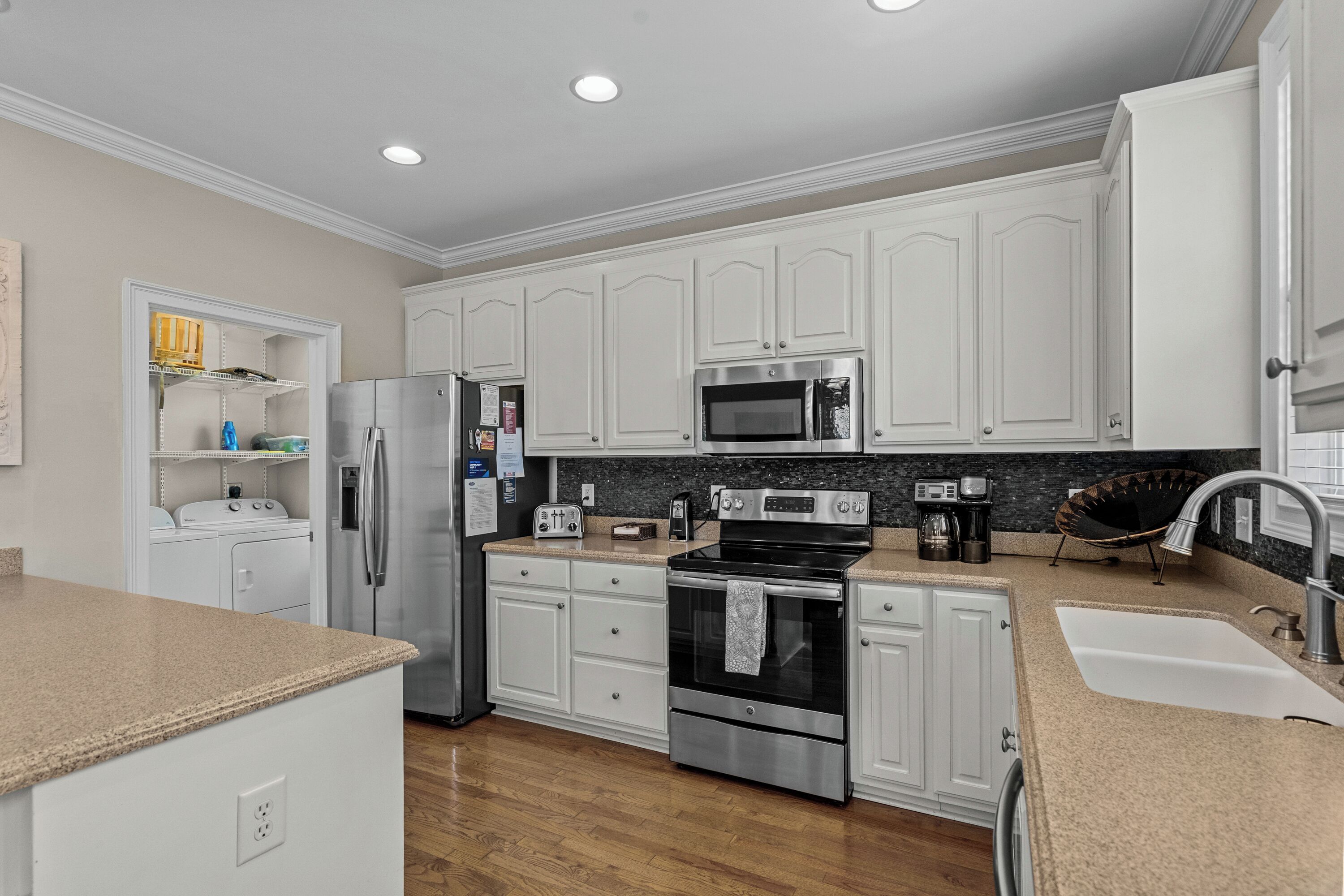 A modern kitchen with white cabinets, stainless steel appliances, and a granite countertop.