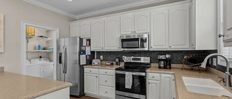 Una cocina moderna con armarios blancos, electrodomésticos de acero inoxidable y encimera de granito.