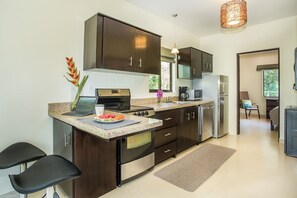 Una cocina moderna con armarios oscuros, horno integrado, microondas y cafetera.