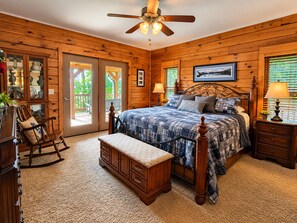 Quarto de cabana de madeira com cama, banco, cômoda e ventilador de teto.