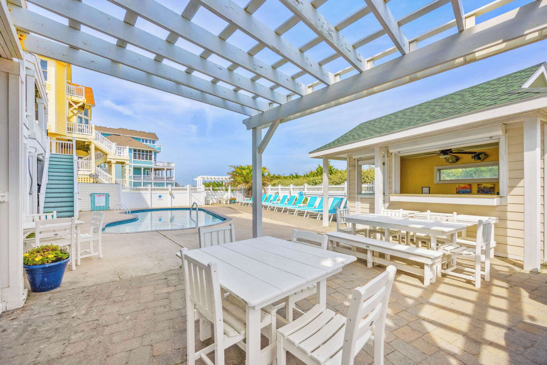 A poolside area with a covered seating area, pool, and outdoor dining space.