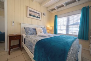A bedroom with a bed, a bedside table, a lamp, and a window with curtains.