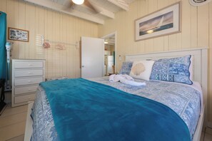 Un dormitorio con cama, cómoda, espejo y puerta que da a un baño.