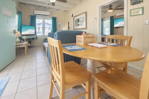 Un comedor con mesa y sillas de madera, un televisor y una ventana con cortinas.