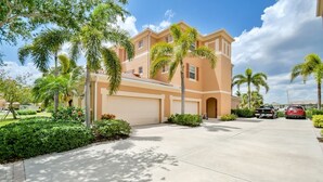 A two-story house with a garage, surrounded by palm trees and well-maintained landscaping. - 3 Bedroom 2 Bath 2 Car Garage includes Golf Cart Usage (Punta Gorda)