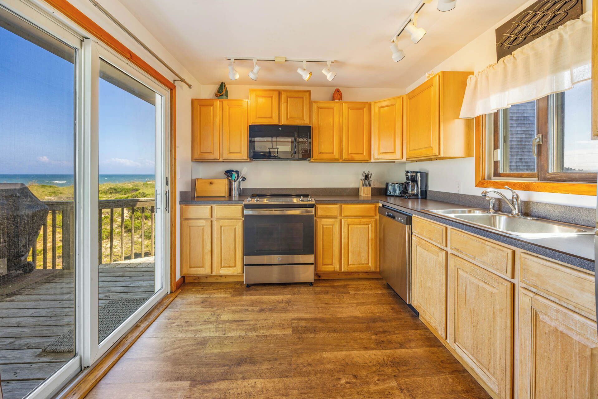 A kitchen with wooden cabinets, stainless steel appliances, and a view of the ocean.