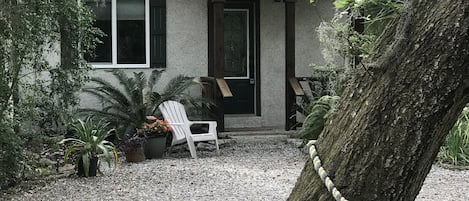 A house with a gravel driveway, a front porch, and a large tree with a rope barrier.