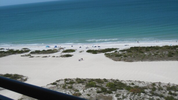 A beach with clear skies, sandy shore, and sparse vegetation. - Beachfront Gulf View Retreat on Sand Key Beach (Clearwater)