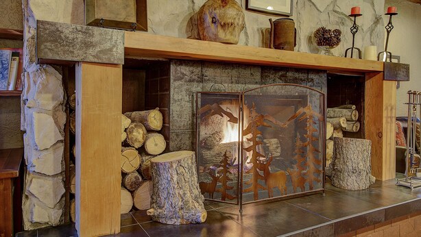 A stone fireplace with a wooden mantel, logs, and a decorative screen. - Park City Resort Ctr 3BR 2Ba Walk2Ski; Free bus Main St; Hot Tub; Winter Pool (Park City)