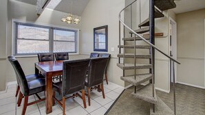 A dining area with a wooden table and chairs, a staircase with a metal railing, and a window with blinds. - Park City Resort Ctr 3BR 2Ba Walk2Ski; Free bus Main St; Hot Tub; Winter Pool (Park City)
