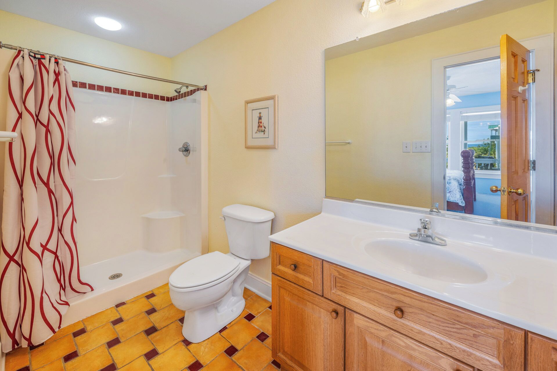 A bathroom with a shower, toilet, and vanity with a mirror.