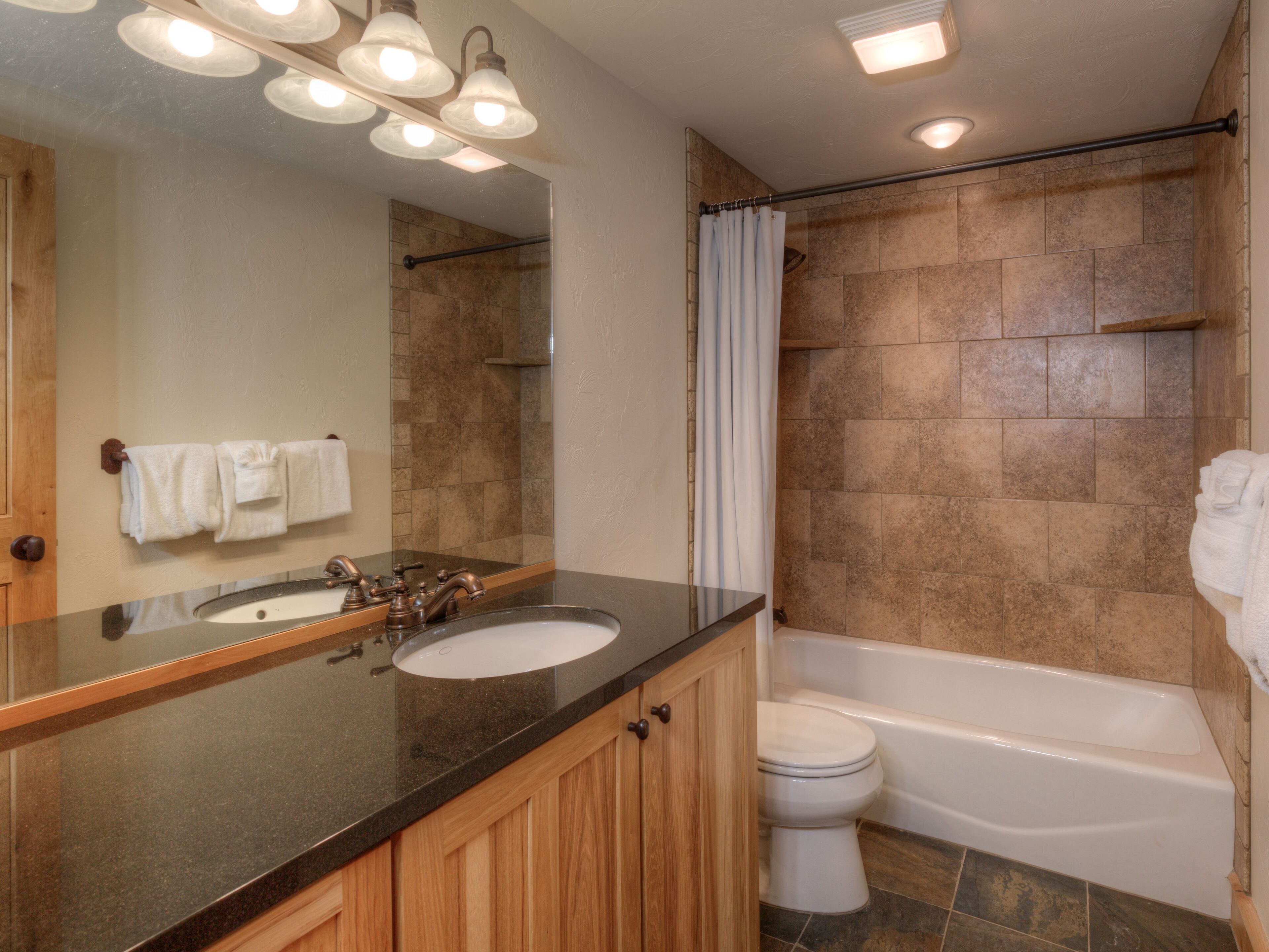 A bathroom with a sink, mirror, and bathtub.
