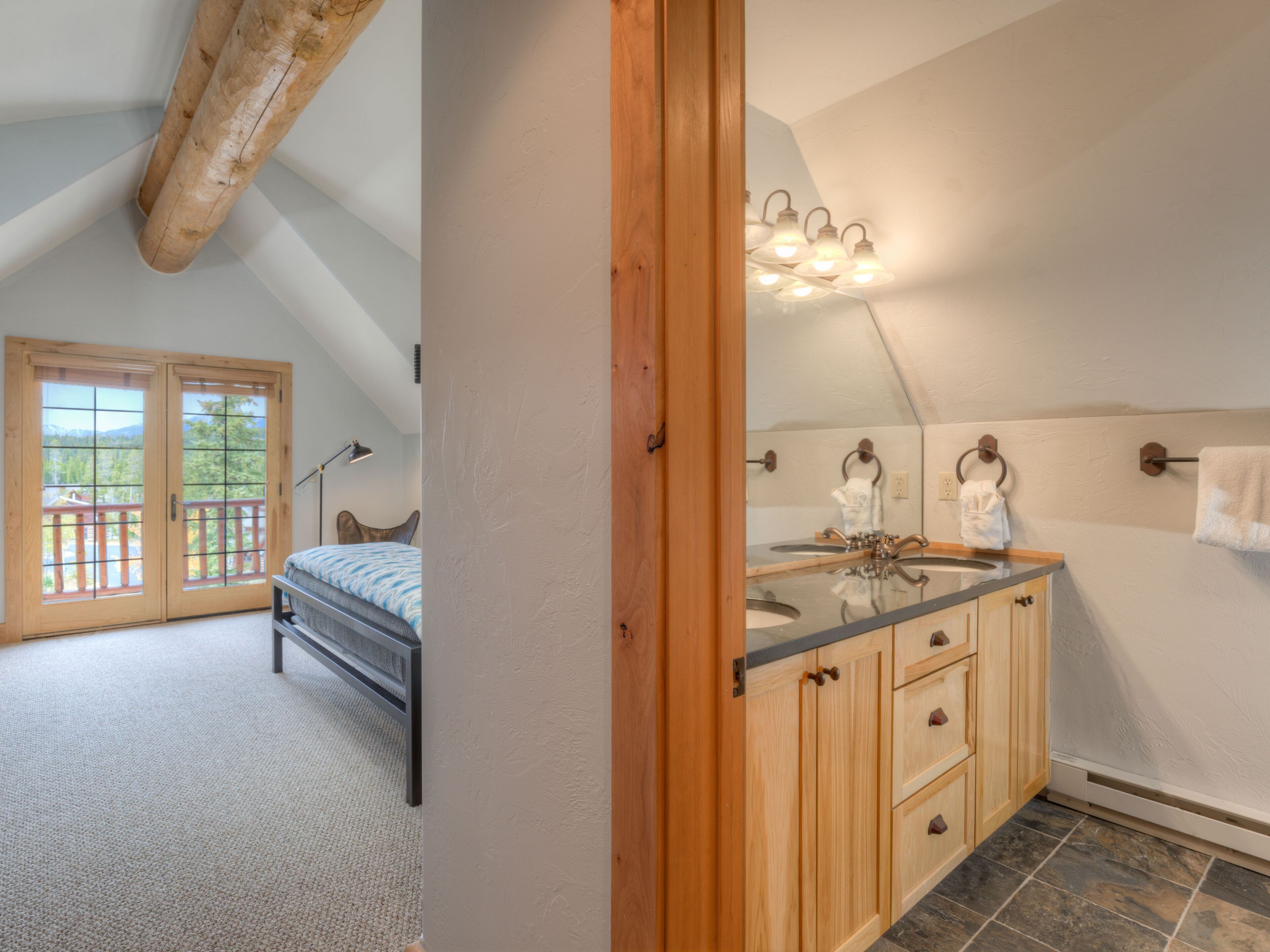 A bedroom with a bed, a wooden door, and a view of the outdoors.