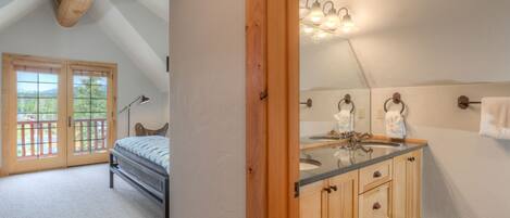 A bedroom with a bed, a wooden door, and a view of the outdoors.
