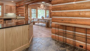 A log cabin interior with a kitchen, dining area, and a fireplace.