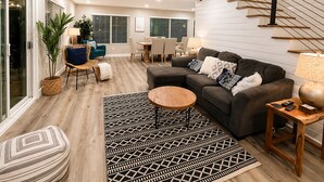 A modern living room with a sofa, coffee table, and a staircase. - Clear Sky Paradise - Pool, Spa & Sunset Vibes (San Diego)